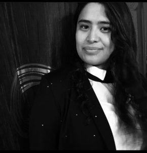 Black and white image of Mayra Castrejon-Hernandez wearing a white collared shirt and a black jacket with a slight grin on her face.